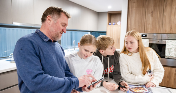 Plico family checking their energy monitoring app in their kitchen 